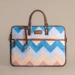 Tissli handwoven rug laptop bag with blue and peach chevron pattern and premium brown leather handles.