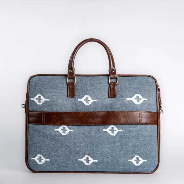 Slate grey handwoven rug laptop bag with white eye-shaped geometric patterns and brown vegan leather handles.
