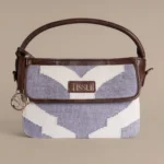 Handwoven lavender and cream rug handbag with dark brown leather handle and gold Tissli logo charm.