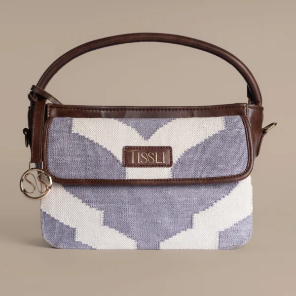 Handwoven lavender and cream rug handbag with dark brown leather handle and gold Tissli logo charm.