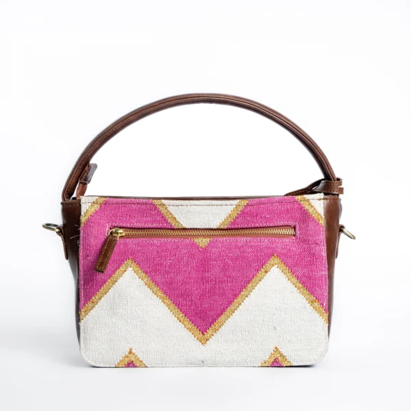Back view of Tissli pink and gold handwoven rug handbag showing a secure horizontal back zip pocket.