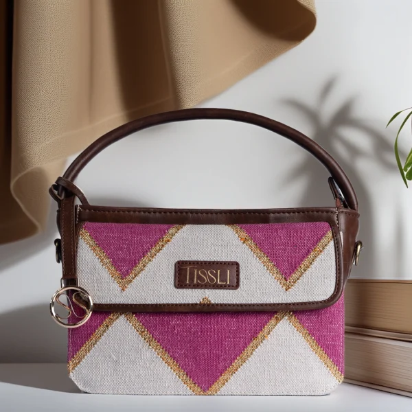 Tissli pink and gold handwoven rug handbag styled with books and elegant beige drapery.