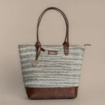 Handwoven charcoal and cream striped rug tote bag with a premium leather base and Tissli gold charm.