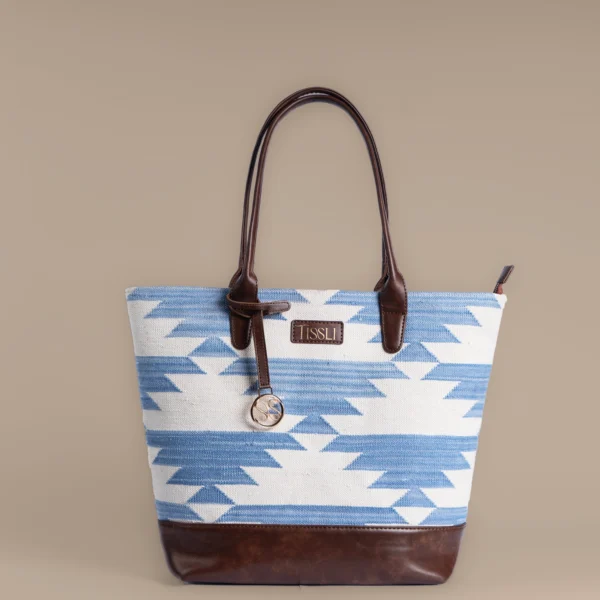 Handwoven blue and white geometric rug tote bag with premium brown leather base and handles by Tissli.