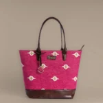 Handwoven magenta pink rug tote bag with white and gold motifs and brown leather base by Tissli.