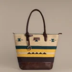 Handwoven mustard and green rug tote bag with tribal motifs, leather base, and Tissli gold logo charm.