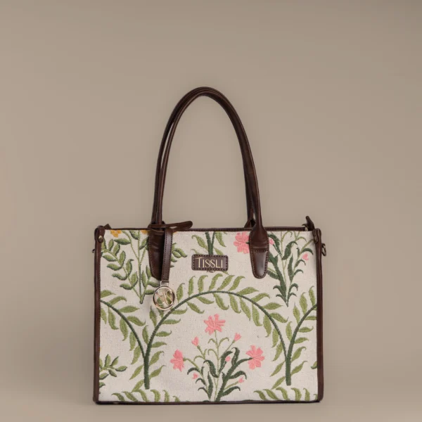 Front view of Tissli Tote showing detailed floral embroidery on a cream handwoven rug base.