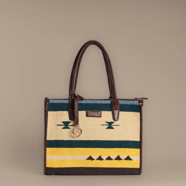 Structured mustard and green handwoven rug tote with tribal motifs and brown leather handles by Tissli.